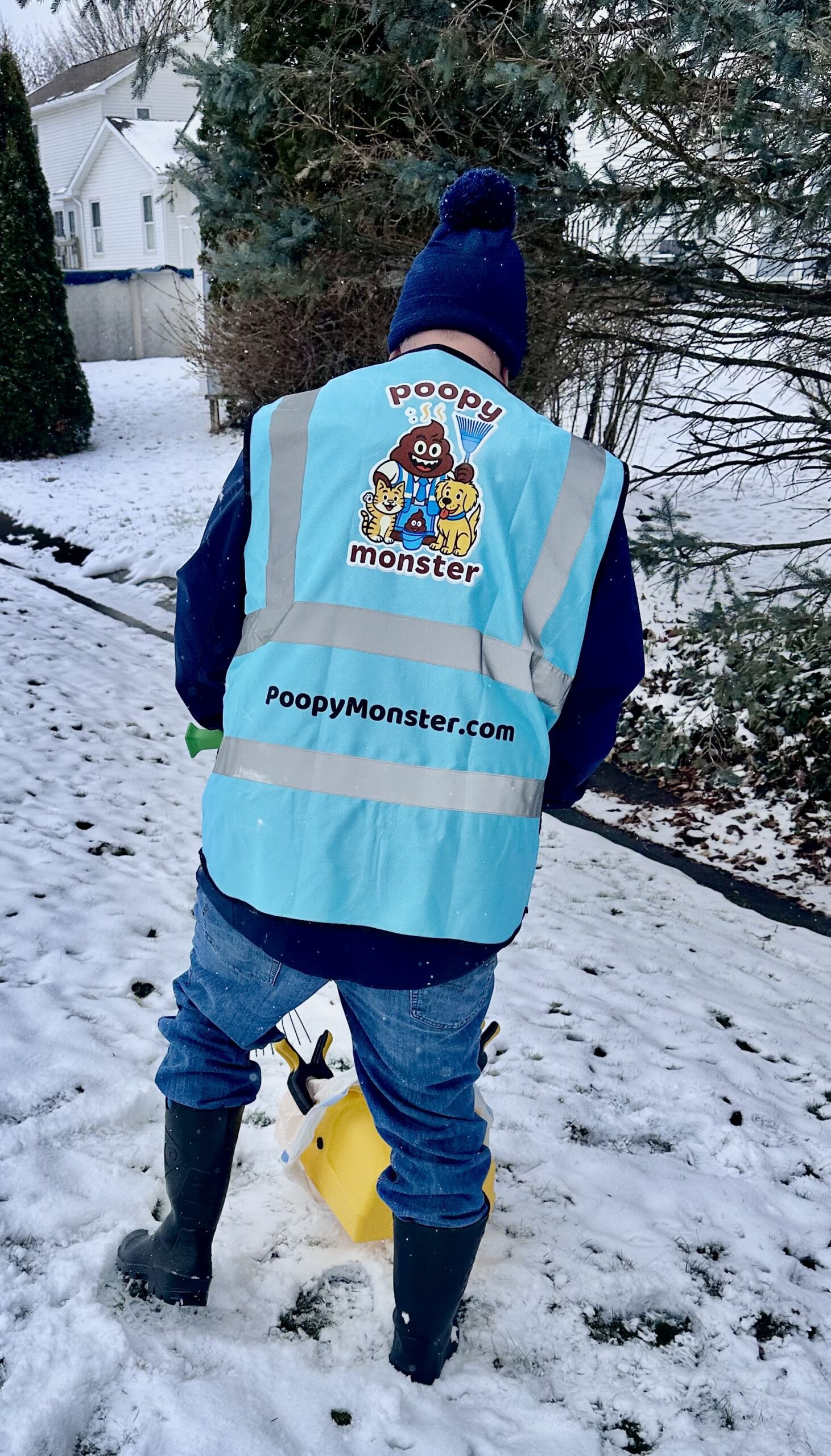 Poopy Monster technician performing winter dog poop cleanup in snowy Rochester backyard wearing branded safety vest